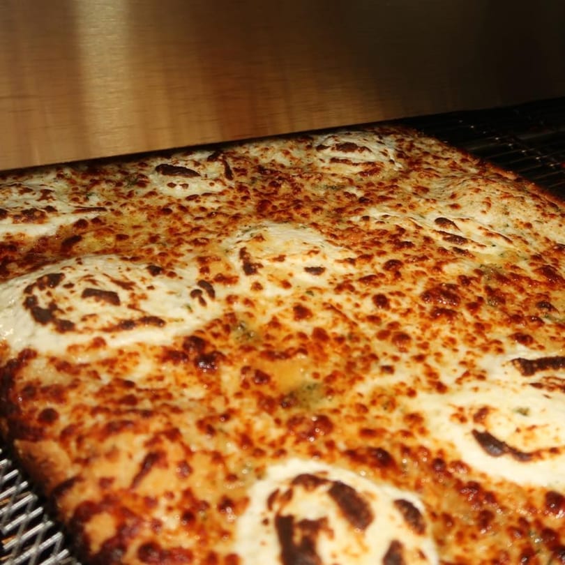 A close-up of a Malatesta's pizza with melted, bubbly cheese and a golden-brown crust.