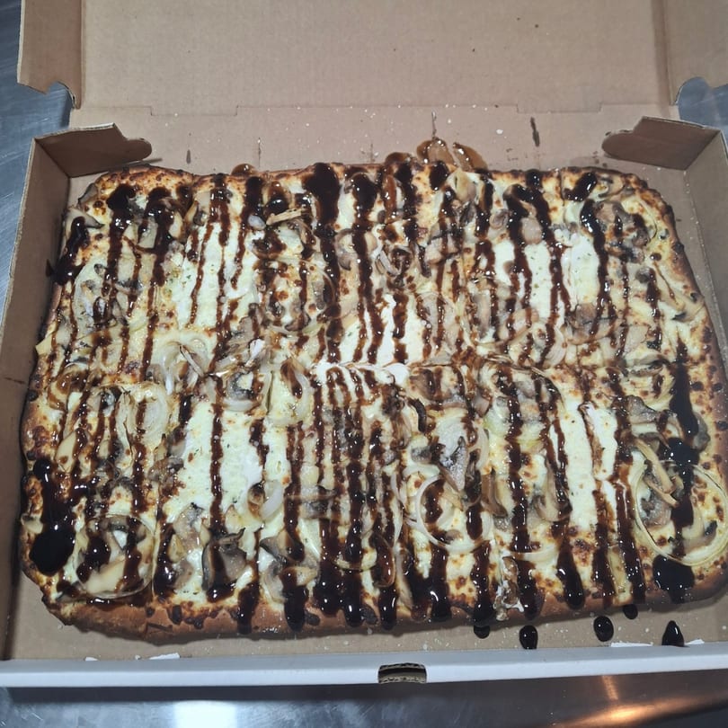 Malatesta's rectangular pizza with white sauce, mushrooms, onions, and a balsamic glaze drizzle.