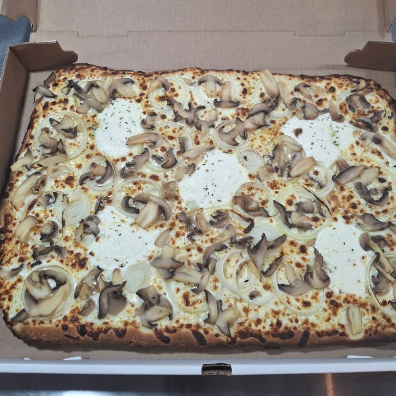 Malatesta's rectangular pizza with white sauce, mushrooms, and onions in a cardboard box.