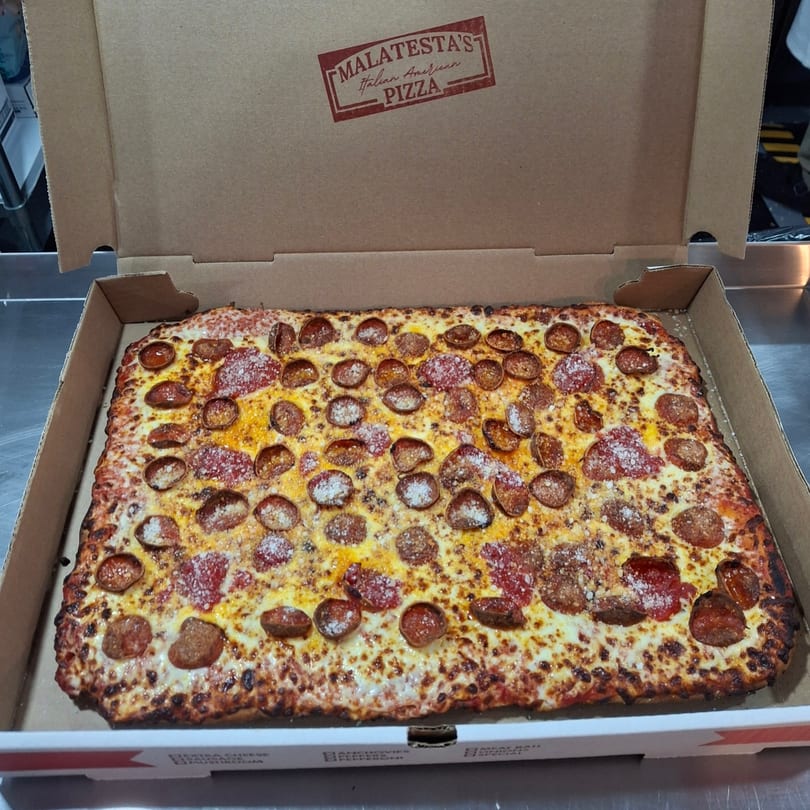 A rectangular Malatesta's pepperoni pizza with melted cheese and parmesan in an open cardboard box.